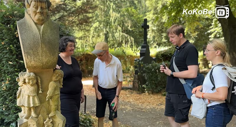 Gruppe von Personen. die um einen Grabstein stehen.